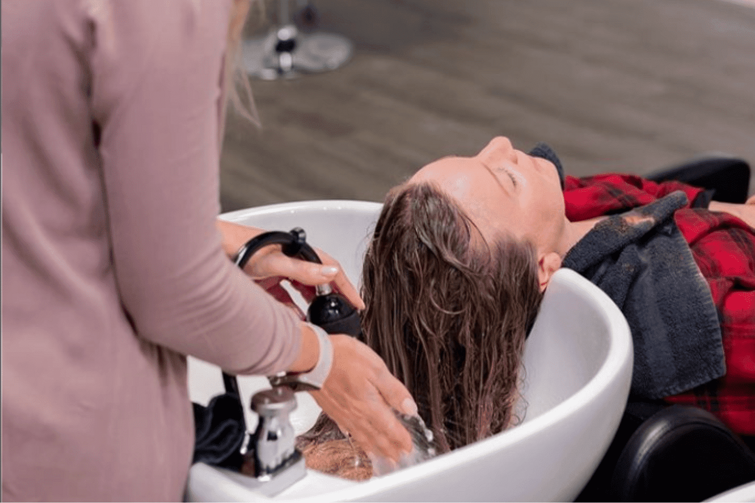 Person getting hair washed at a salon while reclining in a chair.