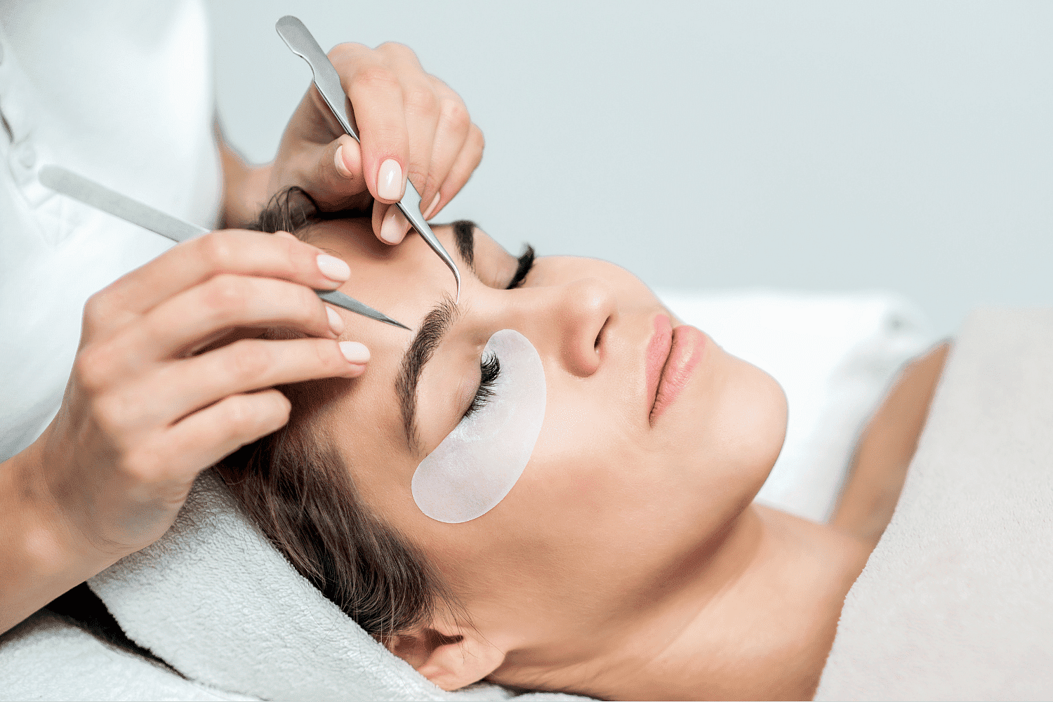 Woman receiving professional eyelash extension treatment at a beauty salon.